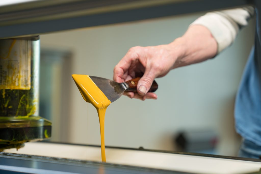 A person putting yellow algae based ink into an industrial printer