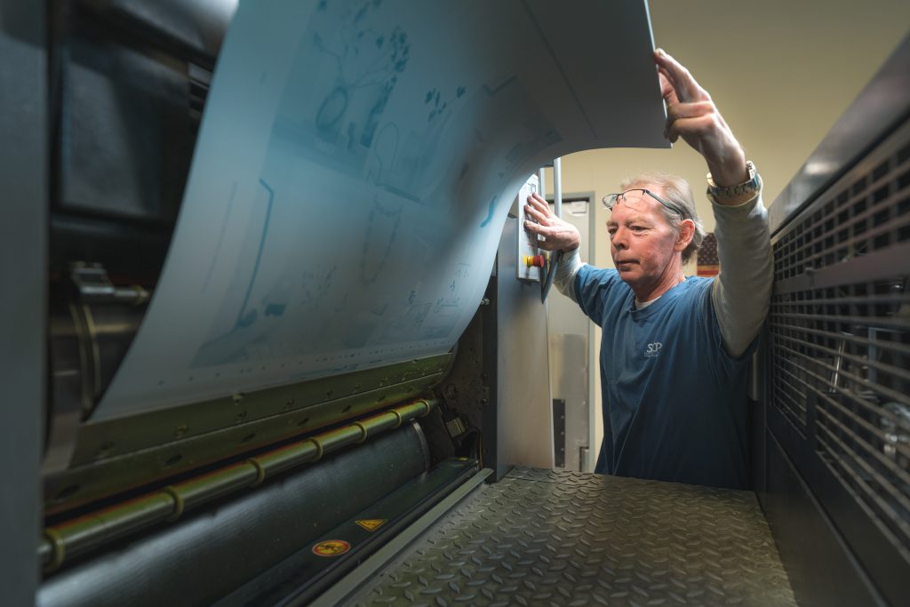 Press operator mounting a plate on an offset press - the traditional method in the offset vs digital printing.