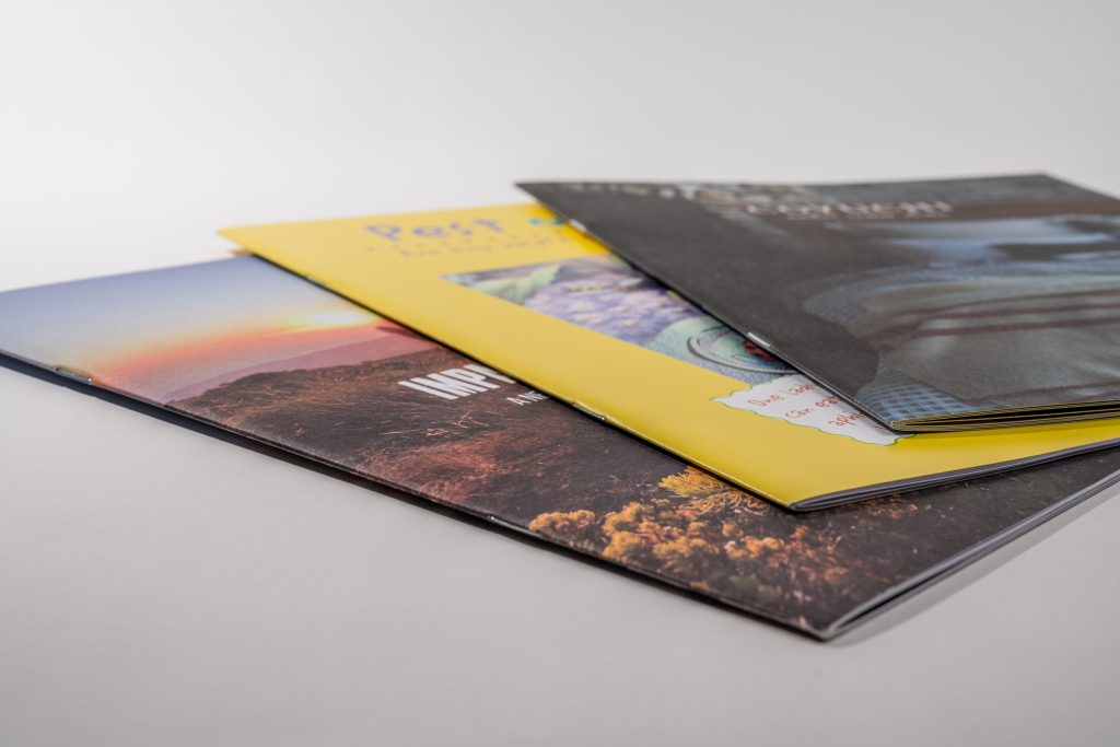 A set of finished saddle-stitched booklets with full-color covers, highlighting the professional look and durability you can expect from saddle stitch booklet printing with Greenrprinter.
