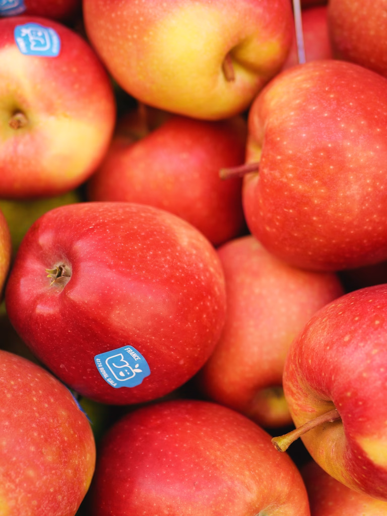 red apples gathered all together with an apple sticker showing on a few