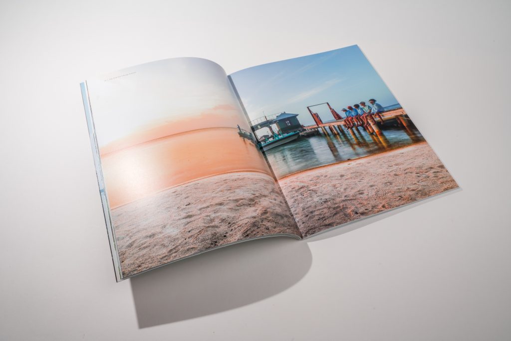 Large booklet opened to spread showing an image of a beach.