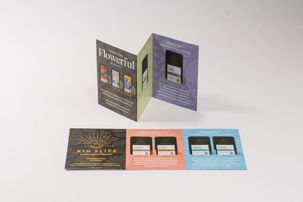 Two printed Kin Slips promotional cards, one standing accordion-style and one lying flat.