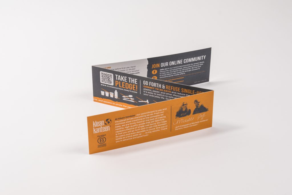 An unfolded orange and dark grey Klean Kanteen informational brochure sitting on a white background.