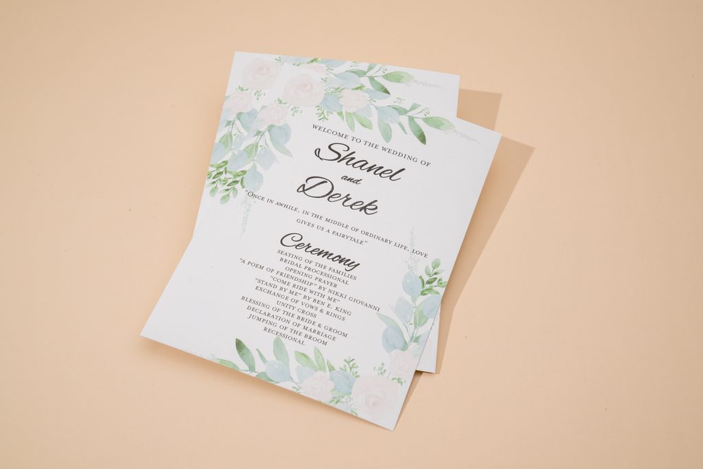 Elegant printed wedding program lying on a ceremony chair with flowers nearby