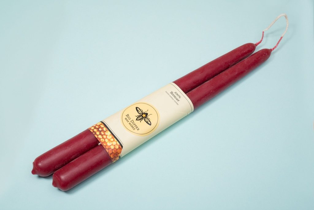 Image shows a pair of candles with a belly band sleeve to hold them together.
