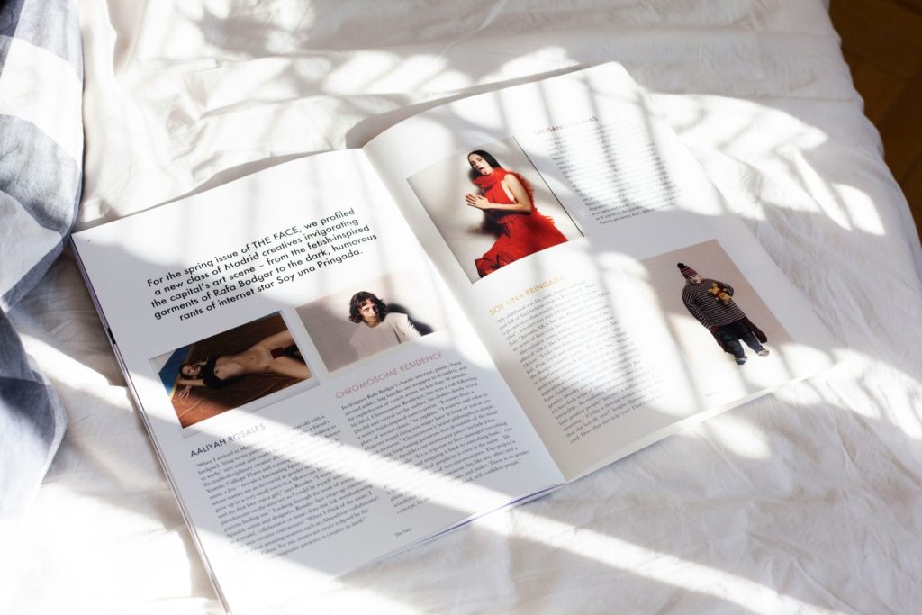 Open fashion magazine on a white bed